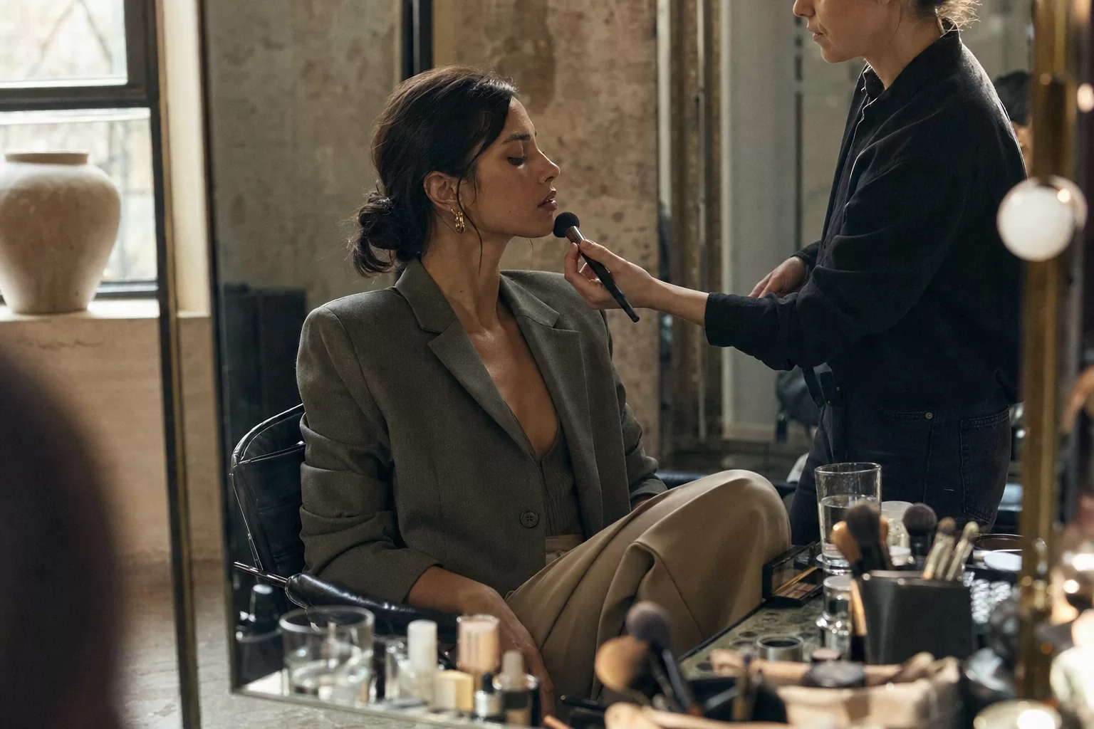 Fashion model receiving a final makeup adjustment before an editorial shoot